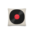 A square throw pillow in a light beige fabric, featuring a graphic print of a black vinyl record with a red center label that reads 'THE SECOND DROP