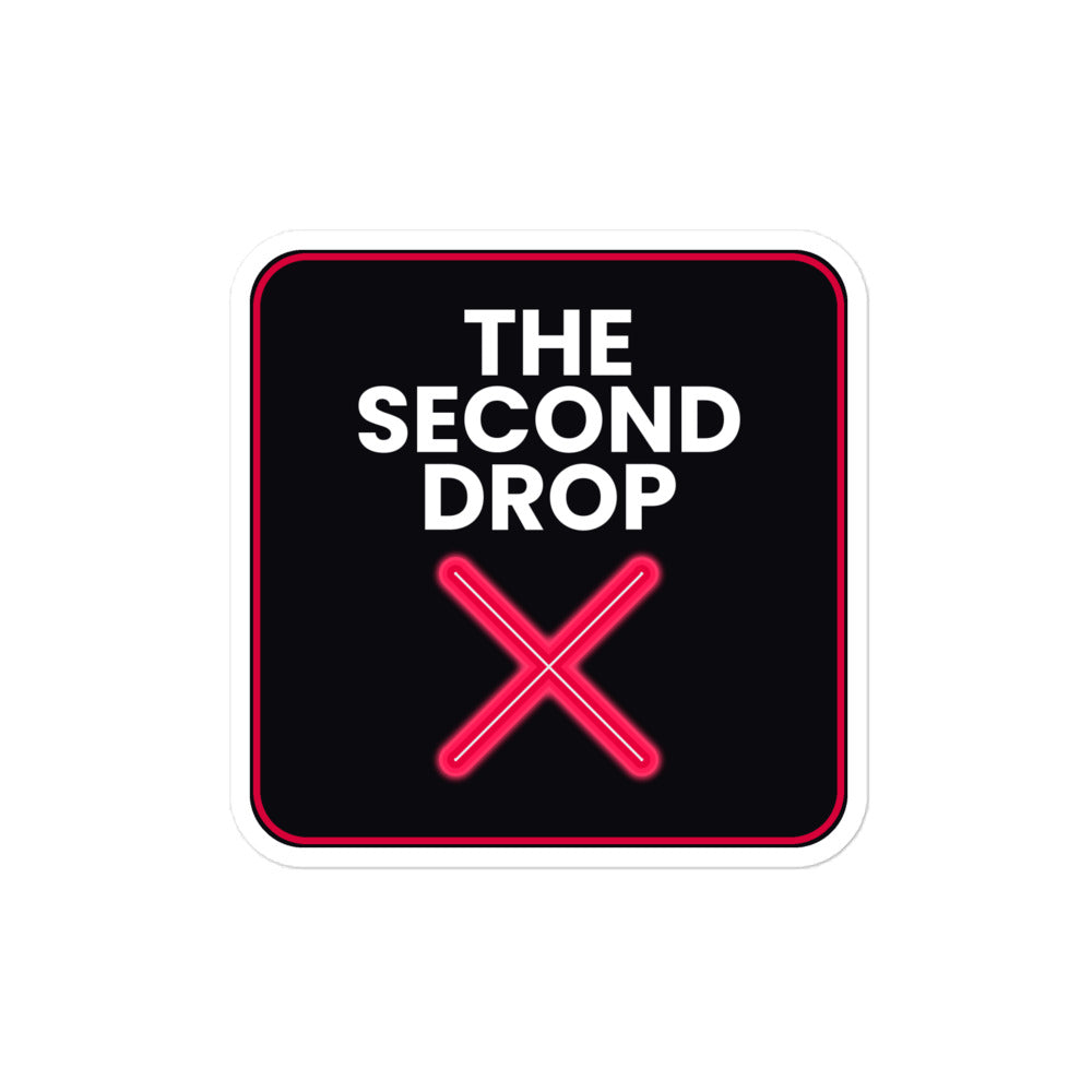 A square sticker or sign with rounded corners featuring the text 'THE SECOND DROP' in white on a black background, with a bright red neon-style X below and a thin red border around the edge.