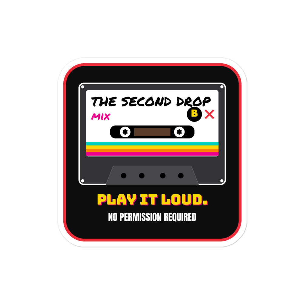 A square sticker or decal with rounded corners featuring a retro cassette tape graphic. The design has a black background with a red border, a white cassette face, and colorful rainbow stripes. The Second Drop. Play It Loud. No Permission Required. 