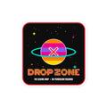 A square sticker or decal with rounded corners featuring a retro space design. The center shows a colorful striped planet with a red 'X' and a teal ring, set on a black starry background.