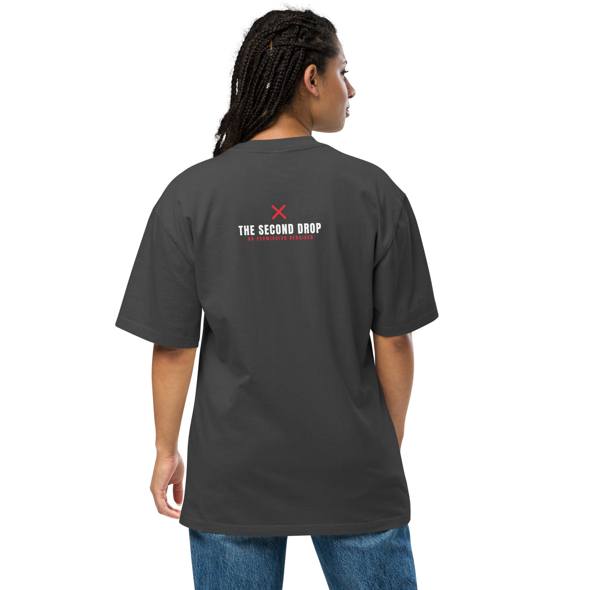 A woman shown from the back wearing a dark charcoal gray t-shirt with a small white and red graphic on the upper back that reads 'THE SECOND DROP'. She is also wearing blue jeans, set against a plain white studio background.