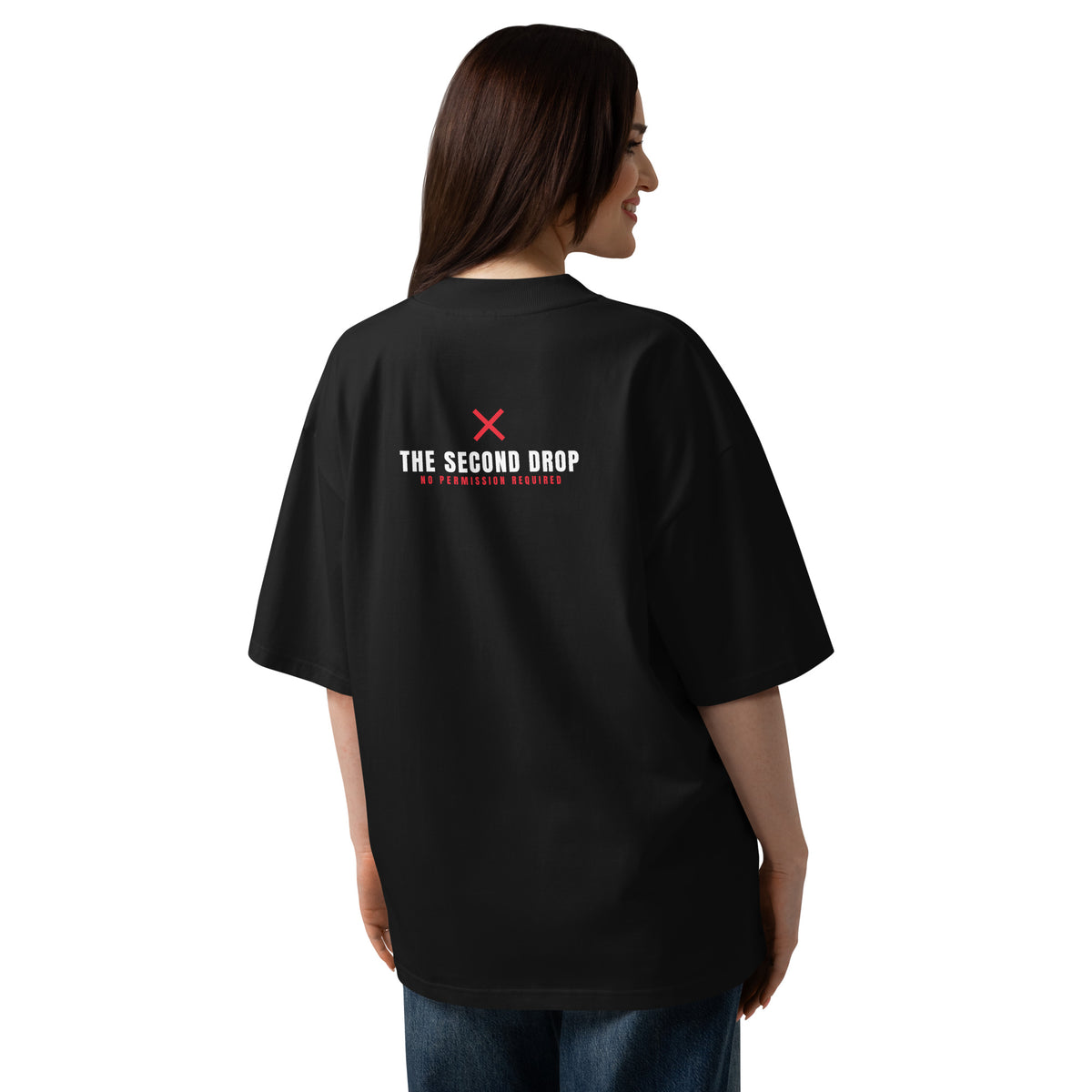 A woman modeling an oversized black t-shirt showing the back with THE SECOND DROP. No Permission Required and a red X