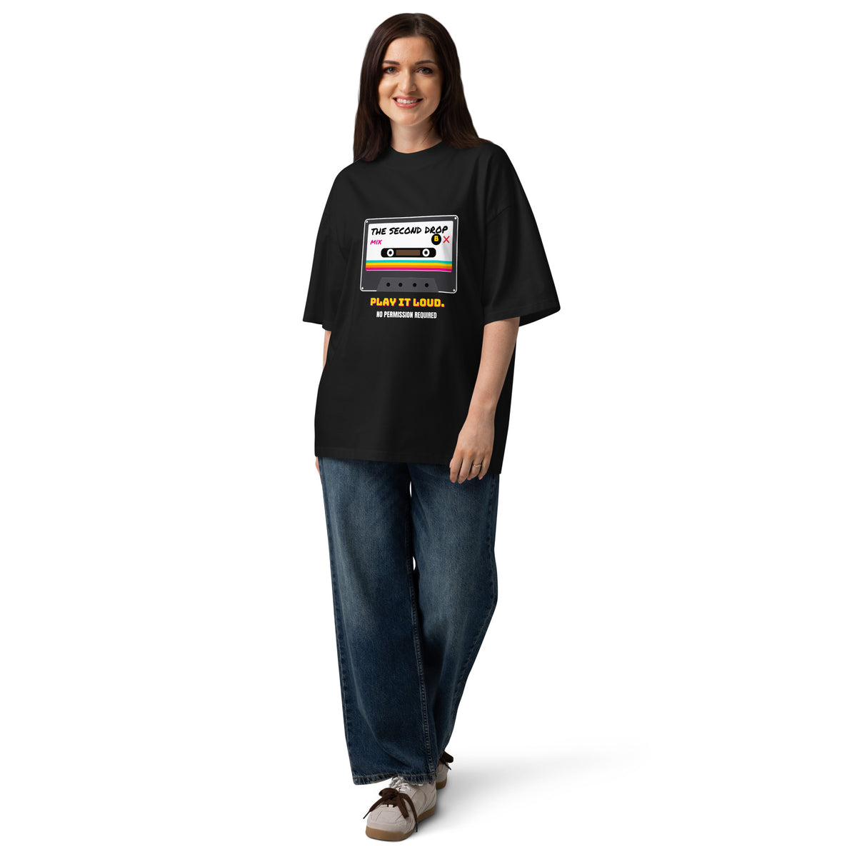 A woman modeling an oversized black t-shirt with a retro cassette tape graphic that reads 'THE SECOND DROP. PLAY IT LOUD" No Permission Required